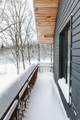 a deck covered in snow next to a house at Sniegi Apartments with sauna in Madona