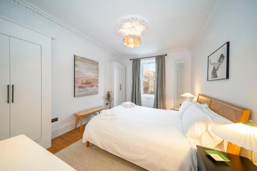 biała sypialnia z łóżkiem i żyrandolem w obiekcie Regal Residence w mieście Broughty Ferry