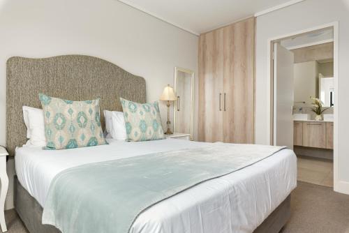 a bedroom with a large white bed with blue pillows at Waters Edge Apartments in Cape Town