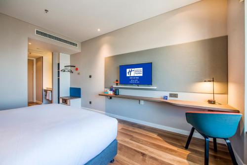 a bedroom with a bed and a tv on a wall at Holiday Inn Express Foshan Beijiao by IHG in Shunde