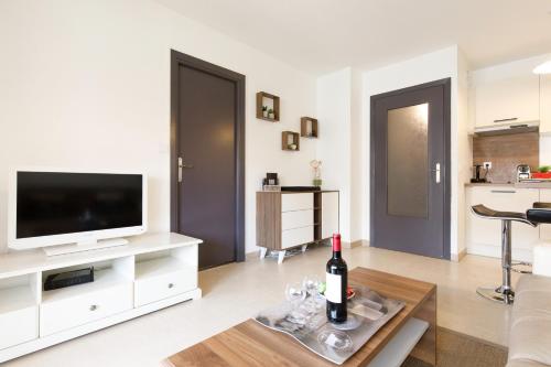 een woonkamer met een televisie en een fles wijn op een tafel bij Le Charme YourHostHelper in Cannes