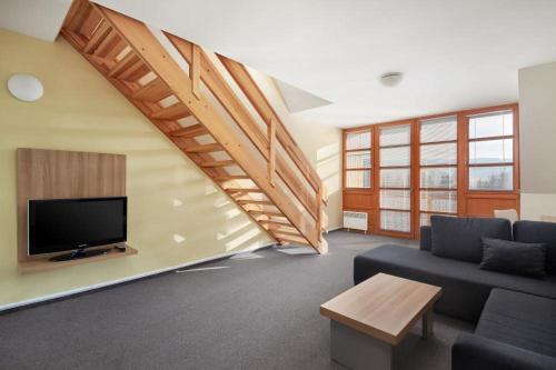 a living room with a couch and a tv at Wellness Hotel Říčky in Říčky