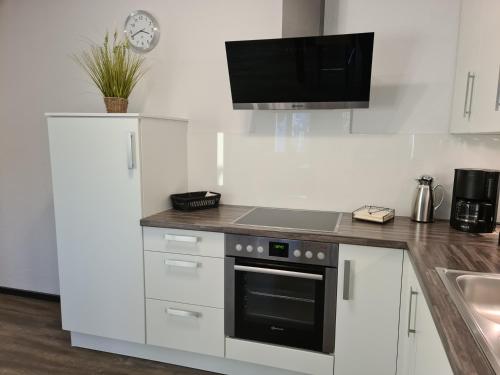 a kitchen with white cabinets and a stove top oven at Ihr Ostseedomizil, im Ortskern von Kellenhusen, strandnah und mittendrin in Kellenhusen
