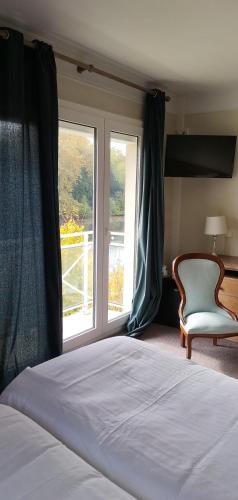 a bedroom with a bed and a chair and a window at Hotel Le Rivage in Olivet