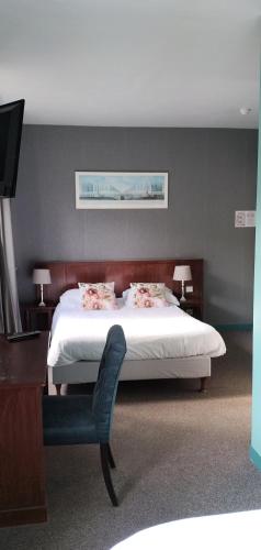 a bedroom with a white bed and a chair at Hotel Le Rivage in Olivet