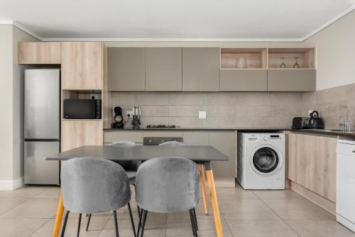 a kitchen with a table and chairs and a washer and dryer at Waters Edge Apartments in Cape Town