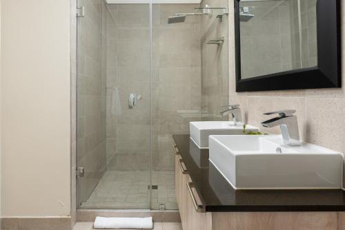 a bathroom with two sinks and a glass shower at Waters Edge Apartments in Cape Town