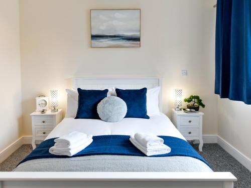 a bedroom with a white bed with blue pillows at Swansea Marina - Sleeps 4 - Underground parking in Swansea
