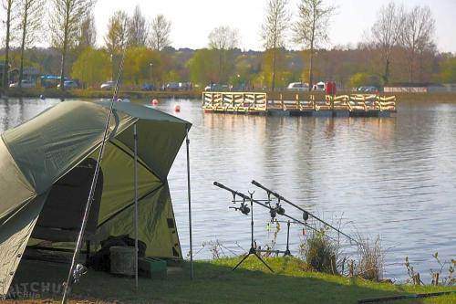 a green tent next to a body of water at Lovely Static Caravan at Billing Aquadrome in Great Billing