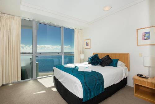 a bedroom with a large bed with a large window at The Grand Apartments in Gold Coast