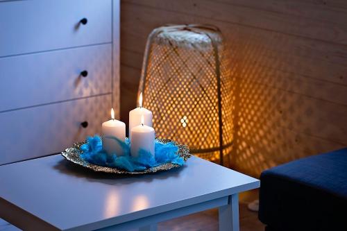 a table with two candles and a lamp on it at Leśna Osada na Kaszubach - drewniane domy na wynajem in Bartoszylas