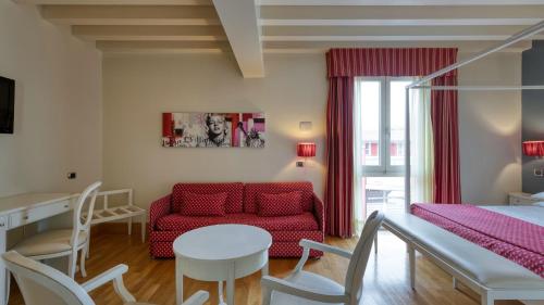 a living room with a red couch and a table at Hotel Fiera Di Brescia in Brescia