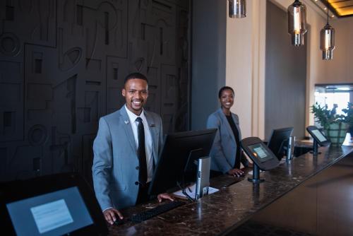 two men in suits standing at a desk with a computer at The Capital Zimbali in Ballito