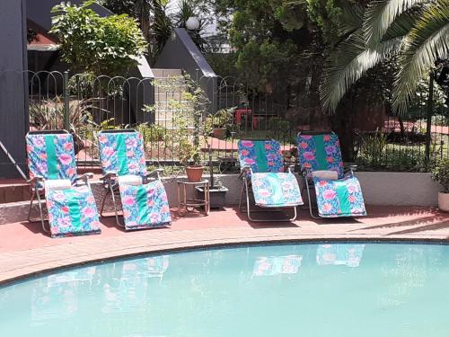 a group of lawn chairs sitting next to a pool at St Michelle Guest Lodge & Hydro Retreat in Alberton