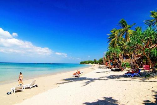 a beach with people sitting on chairs and the ocean at Green Chilli Bungalows in Ko Lanta