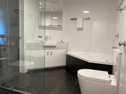 a white bathroom with a toilet and a sink at Mooloolaba Beachfront: Superior Resort Apartment in Mooloolaba