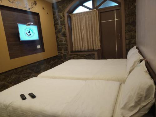 科代卡纳尔Western Valley Home stay的房间里有两张床，墙上有一台电视