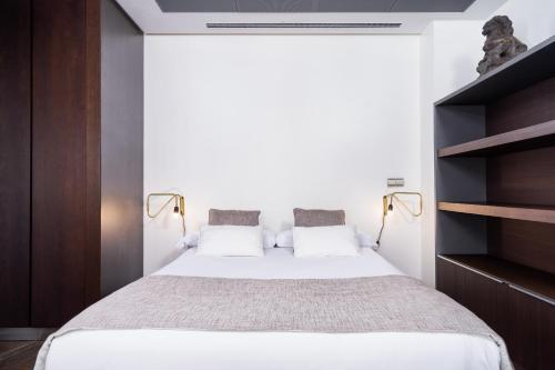 バレンシアにあるBoutique Alma Apartmentsの白いベッドと木製の棚が備わるベッドルーム1室