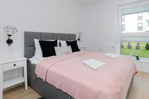 a bedroom with a bed with a pink blanket and a window at Nadmorskie Tarasy Gdynia by Renters in Gdynia