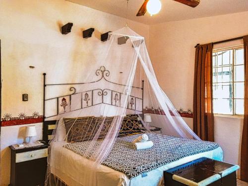 a bedroom with a bed with a mosquito net at Private Beachhouse Hacienda Antigua in El Cuyo