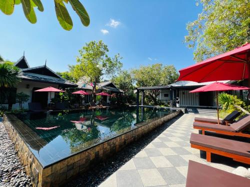 a swimming pool at a resort with red umbrellas at Na Mantra Resort in Chiang Mai