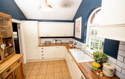 a kitchen with white cabinets and a sink at Annacloy Cottage in Downpatrick