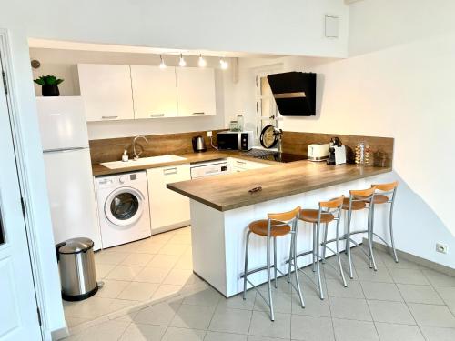 una cocina con armarios blancos y una barra con taburetes en Bel appartement 4 étoiles Centre Historique Toulon, en Toulon