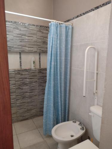 a bathroom with a blue shower curtain and a toilet at Crisol 21 in Huerta Grande