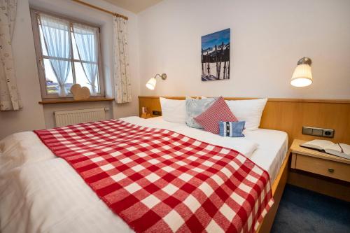 a bedroom with a bed with a red and white checkered blanket at Gemütliche Ferienwohnung Bergwiese, 2-Raum, separates Schlafzimmer, schönen Balkon oder Terrasse, Komfort Ausstattung, ruhige Südlage, kostenfrei WLAN und schöne helle Sauna, Brötchenservice, Parkplatz, Hunde auf Anfrage, E-Tankstelle, Sonnenlage in Balderschwang