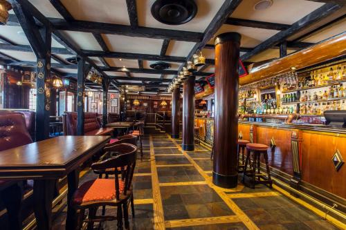 a bar with wooden tables and bar stools at Elite Stadshotellet Eskilstuna in Eskilstuna