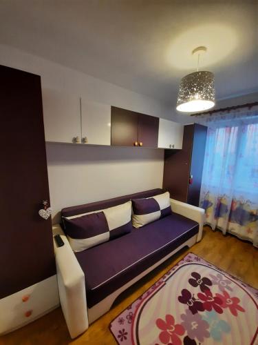 a living room with a purple couch and a rug at Happy apartament in Sibiu