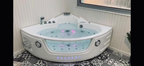 a white bath tub sitting in a room at NG SuiteHome - Lanester Lorient - Balnéo - Netflix - Wifi in Lanester