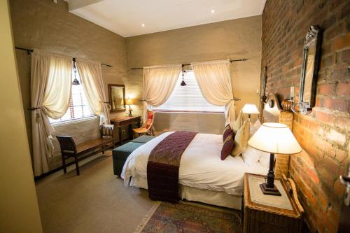 a hotel room with a bed and a desk and windows at Downstream in Dullstroom