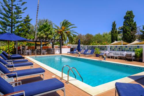 a swimming pool with lounge chairs and umbrellas at Casa Monte Cristo Apartments - Almond in Lagos