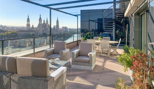 einen Balkon mit Stühlen und Tischen auf einem Gebäude in der Unterkunft Ático mejores vistas al Pilar jacuzzi y garaje in Saragossa