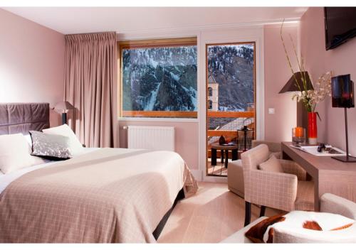 una camera d'albergo con letto, scrivania e finestra di Hôtel & Spa L'Alta Peyra a Saint-Véran