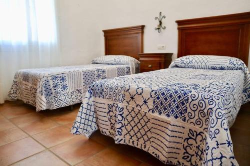 - 2 lits dans une chambre avec des couvertures bleues et blanches dans l'établissement Fuente del Gallo Nomada, à Conil de la Frontera