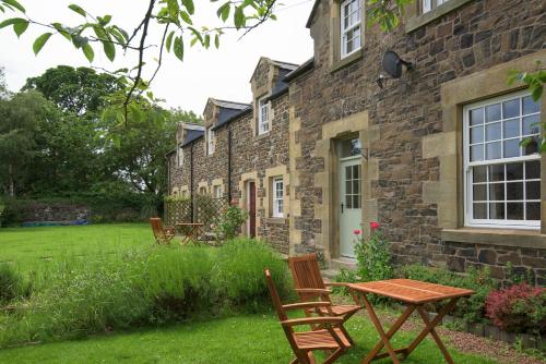 ein Steingebäude mit Stühlen und einem Tisch im Hof in der Unterkunft Pol!cehouse Cottages, Embleton in Alnwick