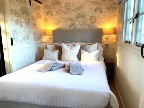 a white bed with pillows and towels on it at Luxury Shepherds Hut with Superb Views & Fire Pit & walking distance to a superb Gastro Pub in Lamerton