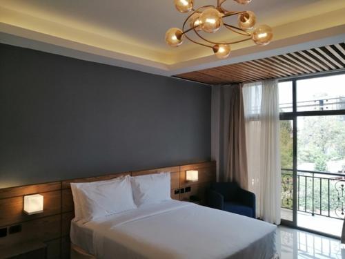 1 dormitorio con cama blanca y lámpara de araña en Mazeki Addis Boutique Hotel en Addis Abeba