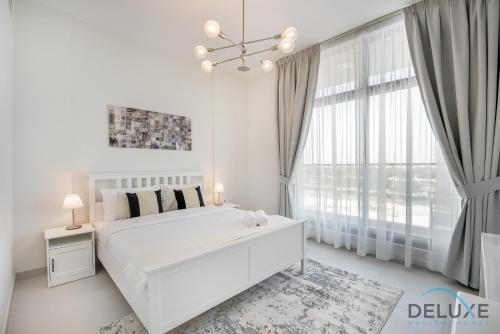 a white bedroom with a white bed and a large window at Stunning 1BR at Prime Views Meydan by Deluxe Holiday Homes in Dubai