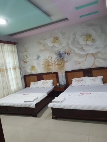 two beds in a room with flowers on the wall at Khách Sạn Trường Thịnh in Ben Tre