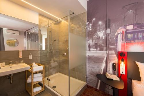 a bathroom with a shower and a sink and a bus at Three Corners Hotel Anna in Budapest