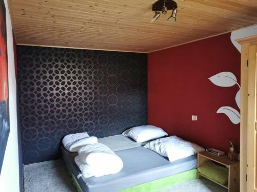 uma cama num quarto com uma parede vermelha em Finnhütte Wolfsburg em Wolfsburg-Unkeroda