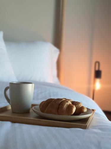 a plate of bread and a cup of coffee on a bed at Cozy 1-bedroom apartment in Dubai South with Pool in Dubai