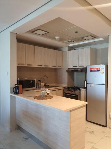 a kitchen with a counter top and a refrigerator at Cozy 1-bedroom apartment in Dubai South with Pool in Dubai