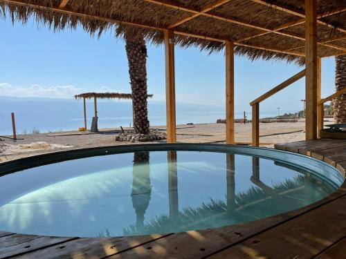 a swimming pool next to a beach with a palm tree at Glamping -420 in Kalia