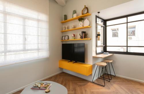 a living room with a tv and a yellow cabinet at De Pejoto in Tel Aviv