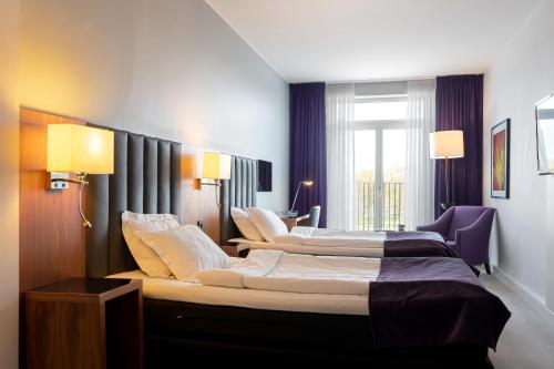 a hotel room with two beds and a window at Elite Stadshotellet Eskilstuna in Eskilstuna
