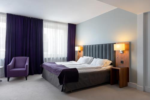 um quarto com uma cama e uma cadeira roxa em Elite Stadshotellet Eskilstuna em Eskilstuna